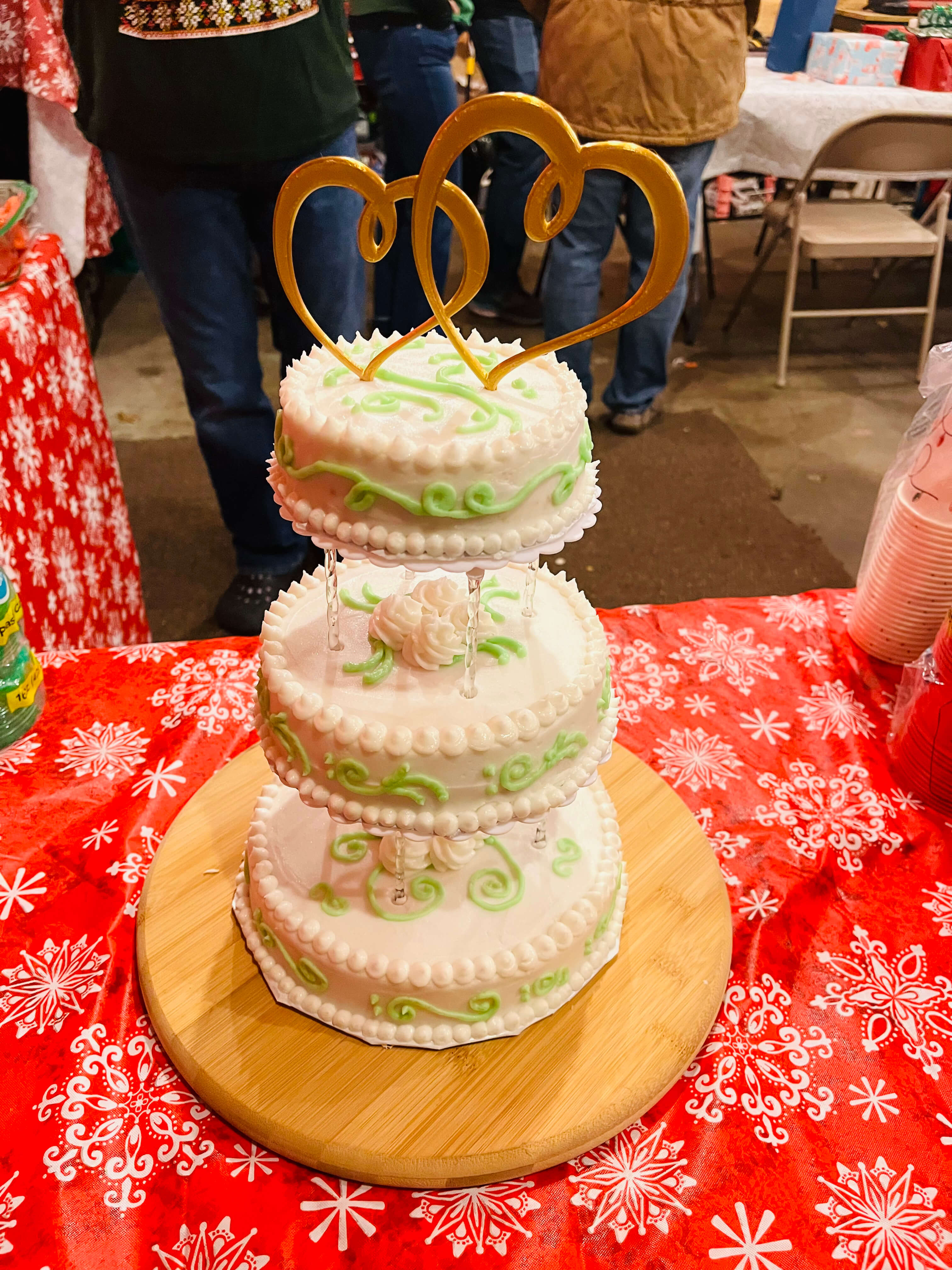 Mini tiered vanilla cake decorated with sage green scroll piping and a beaded border.