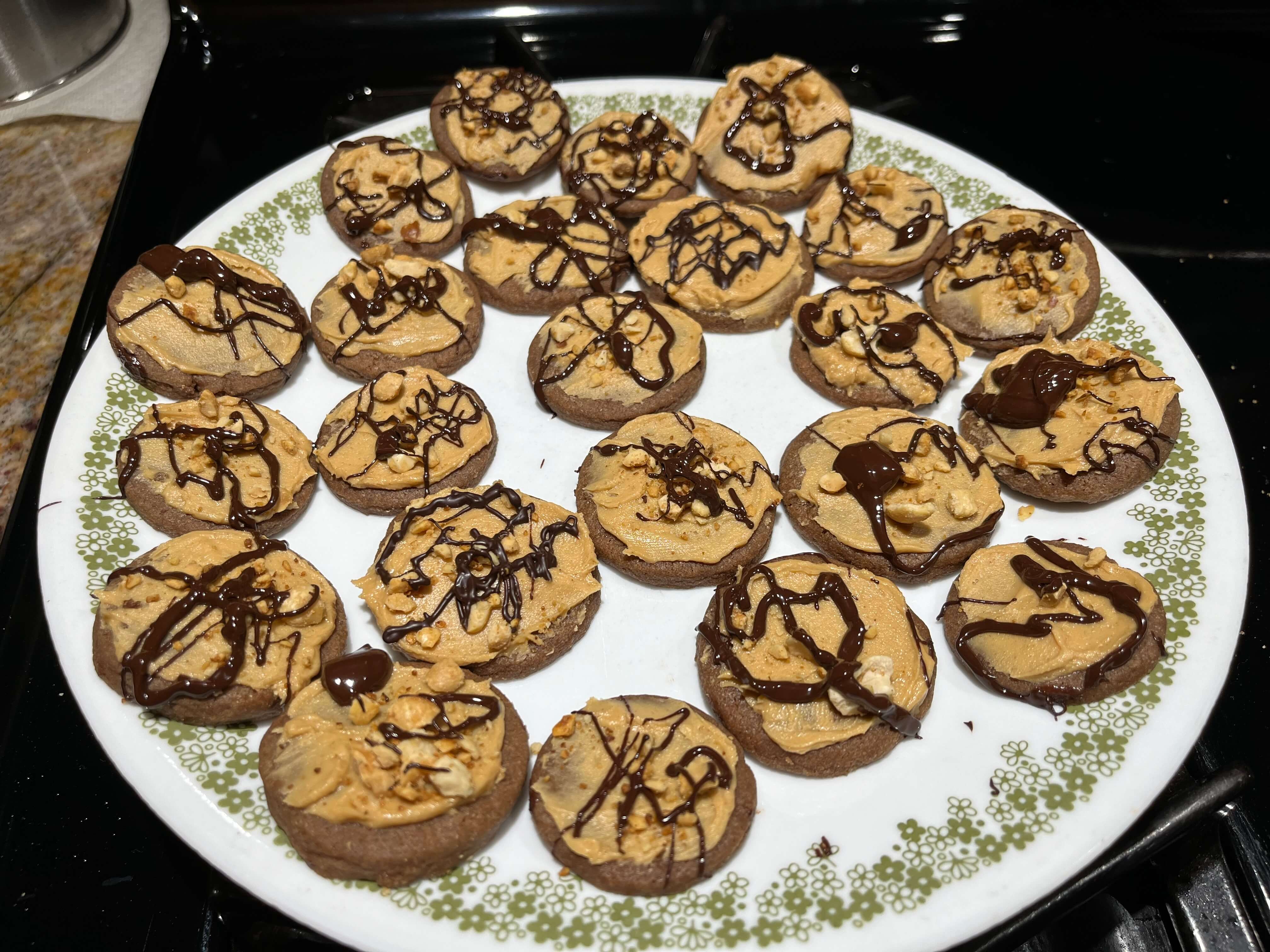 Chocolate cookie base with peanut butter frosting, topped with crushed peanuts and drizzled with dark chocolate.